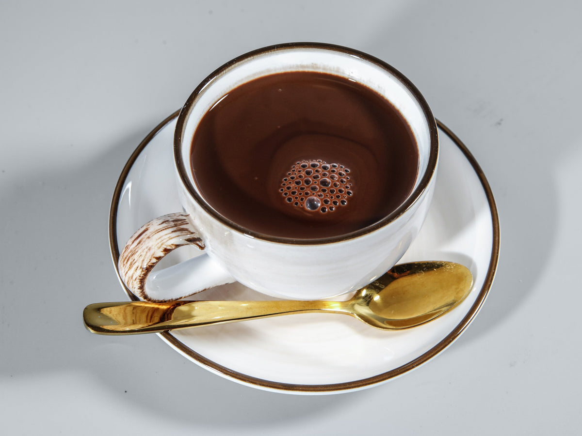 Tasse heiße Trinkschokolade mit goldenem Löffel