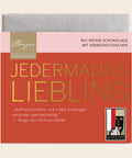 Bio Weiße Schokolade mit Erdbeerstückchen 90g „Jedermanns Liebling“ – Tafelschokolade von Confiserie Berger, 90 g, freigestellt vor cremefarbenem Hintergrund