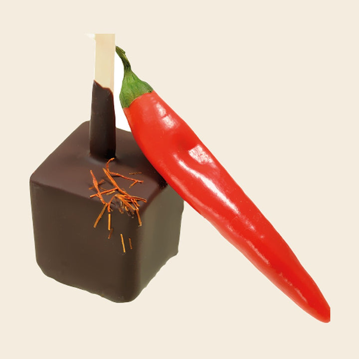 Trinkschokolade Chili – Trinkschokolade am Stiel von Art of Chocolate, 30 g, freigestellt vor cremefarbenem Hintergrund