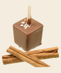 Trinkschokolade Zimt – Trinkschokolade am Stiel von Art of Chocolate, 30 g, freigestellt vor cremefarbenem Hintergrund
