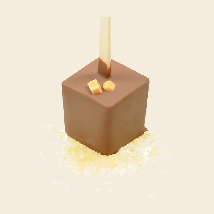 Trinkschokolade Karamell – Trinkschokolade am Stiel von Art of Chocolate, 30 g, freigestellt vor cremefarbenem Hintergrund