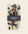Tafel weiße Schokolade mit karamellisierten Mandeln, Cranberries & Pistazienkerne – Tafelschokolade von Art of Chocolate, 130 g, freigestellt vor cremefarbenem Hintergrund
