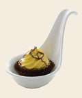 Taste Löffel mit Cupcake: Lemon Cheesecake – Praline von Art of Chocolate, 18 g, freigestellt vor cremefarbenem Hintergrund