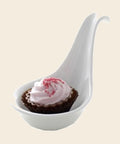 Taste Löffel mit Cupcake: Erdbeer – Praline von Art of Chocolate, 18 g, freigestellt vor cremefarbenem Hintergrund
