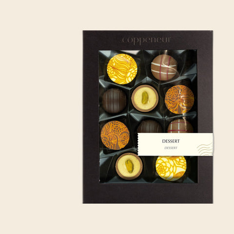 10er Sélection Dessert Pralinés von Coppeneur – Pralinenschachtel freigestellt auf cremefarbenem Hintergrund