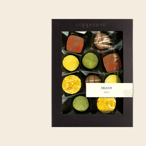 10er Sélection Frucht Pralinés von Coppeneur – Pralinenschachtel freigestellt auf cremefarbenem Hintergrund
