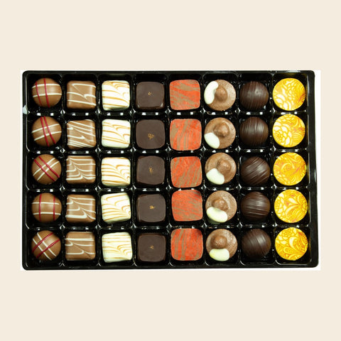 Grande Sélection o. Alk. von Coppeneur – 40 Truffes und Pralinés im Tray auf cremefarbenem Hintergrund