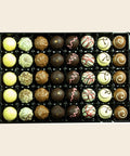 Grande Sélection m. Alk. von Coppeneur – 40 Truffes und Pralinés im Tray auf cremefarbenem Hintergrund