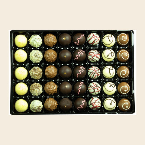 Grande Sélection m. Alk. von Coppeneur – 40 Truffes und Pralinés im Tray auf cremefarbenem Hintergrund
