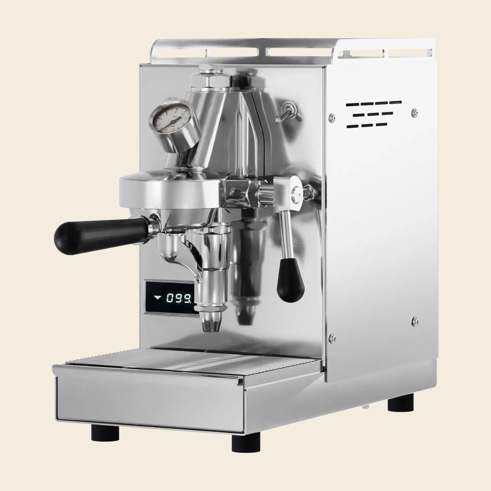 Elba Mini Espressomaschine in Edelstahl mit schwarzen Holzdetails, freigestellt auf cremefarbenem Hintergrund